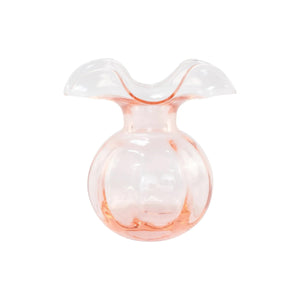 The VIETRI - Hibiscus Bud Vase Pink, designed in a modern style by skilled Tuscan artisans, is a pink-tinted glass vase with a wide, wavy rim and a round base. The transparent Hibiscus Glass features a subtle gradient that showcases delicate craftsmanship.